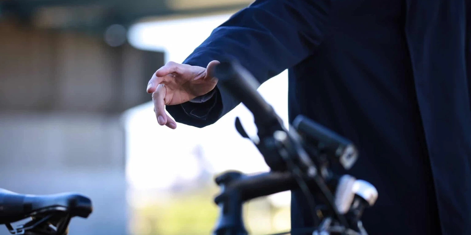 Person mit schwarzer Kleidung greift nach einem Fahrrad