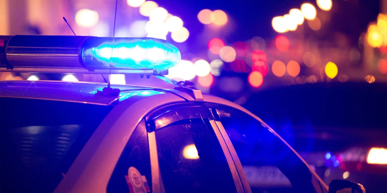Blaulicht auf Dach eines Polizeiautos leuchtet, im Hintergrund Straßenbeleuchtung und Verkehrsbeleuchtung